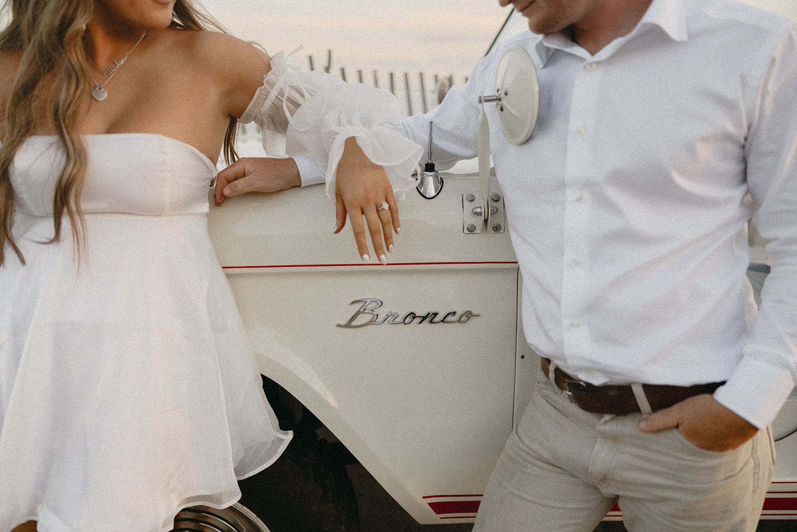 A couple pose in front of their vintage Bronco for their South Carolina beach engagement shoot.