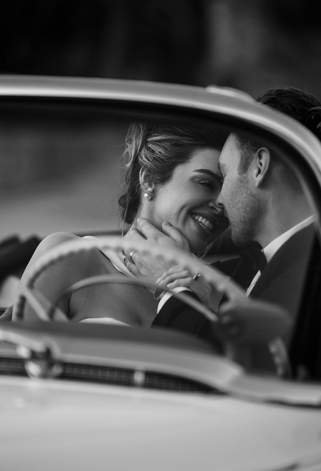A bride and groom share a kiss in their car at their elopement.