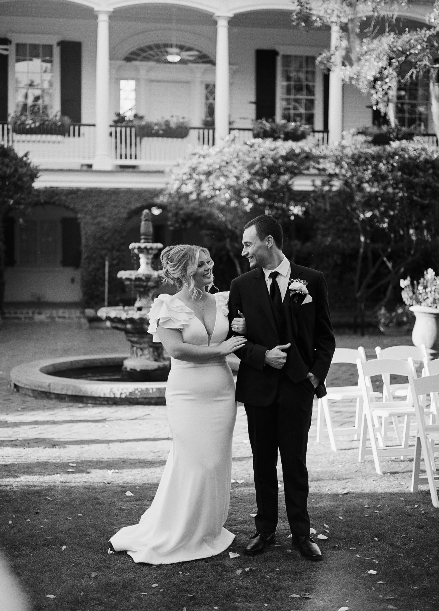 Bride and groom smiling in the garden at the Governor Thomas Bennett House in Charleston, with the fountain and columned piazza behind them