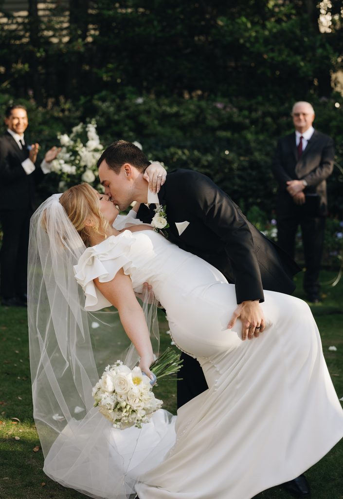 Groom dipping the bride for a kiss at the end of their Thomas Bennett House wedding ceremony as guests applaud