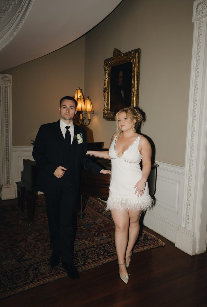 Bride and groom in the curved stair hall at the Governor Thomas Bennett House beneath a historic portrait